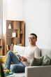 © Pixel-Shot - Male student using tablet computer on sofa at home