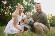 © Serhii - Happy young family spending time together outside in green nature.