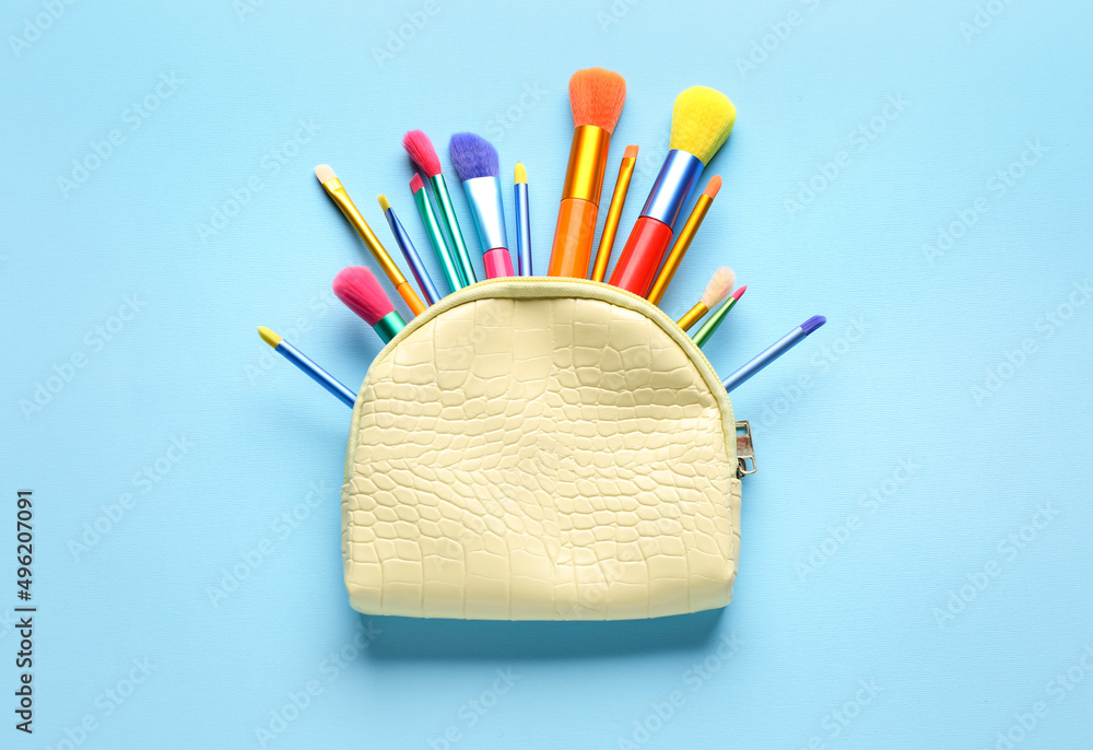 Bag with set of makeup brushes on blue background
