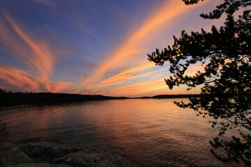 brilliant sunset over northern minnesota fishing lake fills sky with colorful clouds and subtle gold