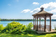 A wood gazebo over looks the Niagara River in Niagara on the Lake, Ontario, Canada on a blue sky day. The United States can be seen in the distance.
