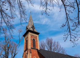 Looking up at a church steeple against a blue sky on a spring day.