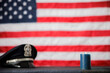 A police hat and burning blue candle in front of an American Flag
