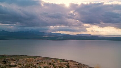 Wall Mural - Storm clouds moving in the distance as light rays shine to the ground looking past Utah Lake.