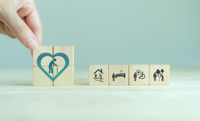 Wall Mural - Elderly care concept. Hand holds wooden cubes with icons related to elderly care, medical, rehabilitation service, nursing care for enhancing quality of life in elder age. Used for banner, background