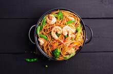 Stir-fried Spaghetti Or Stir-fry Noodles With Vegetables And Shrimp In A Black Bowl. Dark Background, Top View