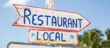 A Sign Saying Local Restuarant Points To The Right In A Tropical Summer Destination, Written On A Rustic Wooden White Board
