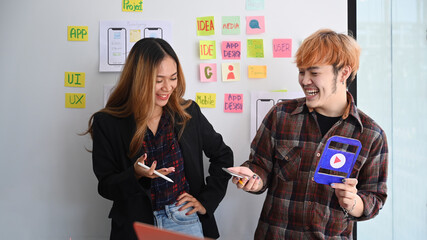 Wall Mural - two happy web designers presenting and testing mobile app interface design on whiteboard at creative
