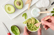 Hands preparing natural avocado skin care cream in home top