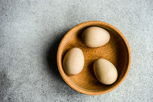 Overhead View Of Three Wooden Easter Egg Decorations In A Bowl On A Table