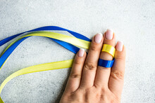 Woman's Hand Holding Blue And Yellow Ribbons To Symbolise Solidarity With Ukraine