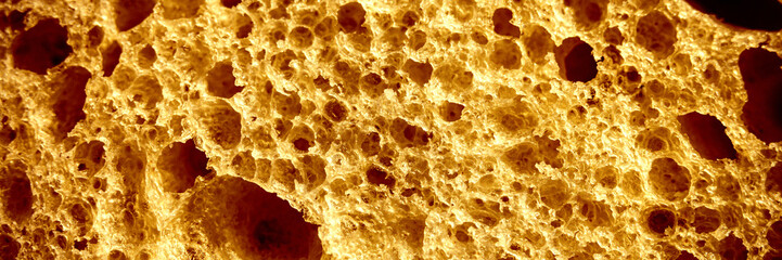 texture of brown bread as a close up background. backdrop of rough dappled textured surface crusty toasted slice of white loaf or sandwich toast of natural organic food with holes. top view. banner