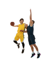 Full-length portrait of two young basketball players jumping with ball isolated on white studio background. Motion, activity, sport concepts.