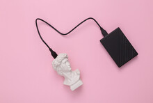 Bust Of David With An External Hard Drive On A Pink Background. Minimal Flat Lay Composition