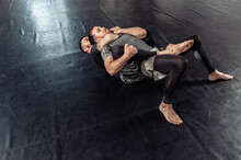 Two Athletic Male Fighters Are Training, Practicing A Painful Hold In A Sports Hall.