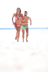 Couple having fun running throughsand on beach.