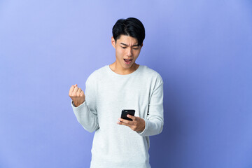 Poster - Young Chinese man isolated on purple background surprised and sending a message