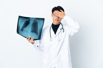 Wall Mural - Young Chinese doctor man holding radiography isolated on white background covering eyes by hands. Do not want to see something