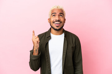 Canvas Print - Young Colombian handsome man isolated on pink background pointing up and surprised