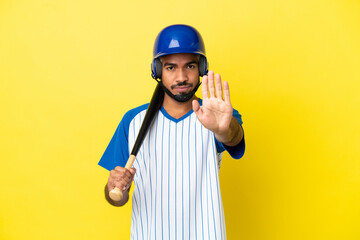 Wall Mural - Young Colombian latin man playing baseball isolated on yellow background making stop gesture