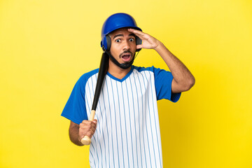 Wall Mural - Young Colombian latin man playing baseball isolated on yellow background doing surprise gesture while looking to the side