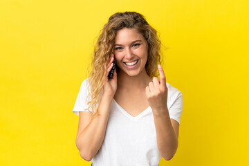 Wall Mural - Young blonde woman using mobile phone isolated on yellow background doing coming gesture