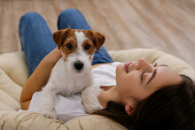 Portrait Of Young Beautiful Woman Lying On A Papasan Chair With Her Adorable Wire Haired Jack Russel Terrier Puppy. Loving Girl With Rough Coated Pup Having A Nap. Background, Close Up, Copy Space.