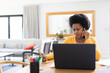© Wavebreak Media - Mid adult african american female freelancer talking on smart phone while working on laptop at desk