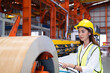 © BritCats Studio - Selective focus at young women inspector wearing safety equipment. While doing audit for quality and safety control inside of factory area. With blurred background of heavy machine.
