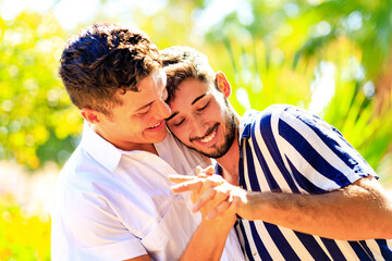 Happy gay couple spending time together in sunny day in green park