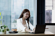 © kamiphotos - A beautiful Asian businesswoman sitting in her private office, she is checking company financial documents, she is a female executive of a startup company. Concept of financial management.