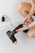 © Anna - The therapist's hand holds a therapeutic percussion massage gun.  The girl puts the vibrating massager on charge. The plug is in the socket. Battery. Sports Physical pain Physical therapy.