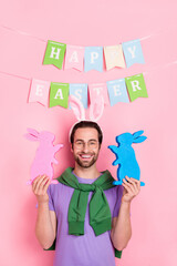 Poster - Photo of good mood handsome cute man celebrate easter hold two little bunny figurines isolated on pink color background