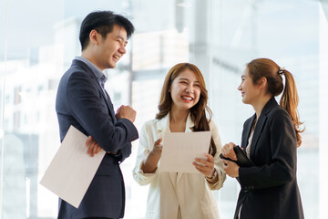 Wall Mural - Group of young Asian business people stand talk, consult, discuss working with new startup project idea presentation analyze plan marketing and investment.