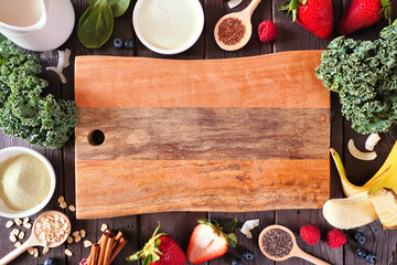 Wall Mural - Healthy food frame with blank board. Smoothie making concept. Top view on a dark wood background. Copy space. Fruit, yogurt, almond milk and an assortment of ingredients.