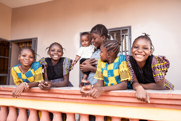 west african mother holding cute little baby boy,surrounded by her four beautiful and cheerful daugh