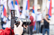 © wellphoto - Filming street protest or demonstration, digital camera in the focus, blurred people in the background