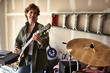 © SuperStock - Portrait of guitar player in Garage band composed of middle aged women, practicing in residential garage