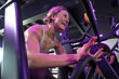 © SuperStock - Young enthusiastic muscular woman working out in gym with magenta lighting.