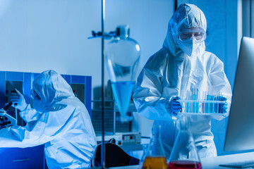 bioengineer holding test tubes while colleague working on background.