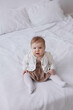 © Tatyana - Sweet  little 1-year-old daughter sitting on chair in grey dress.Portrait of Girl baby child on bed at home. Tenderness and love, sweetness. Lovely family indoors.Serious baby portrait indoors