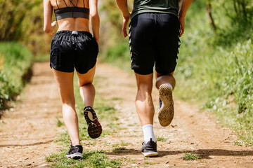 Wall Mural - Sport people running in park together. Young couple jogging at outdoor workout. Fitness woman and man running marathon at sunset in park