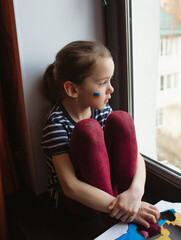 the face of a little girl, a crying child, flowing tears painted on her cheek in the yellow-blue col