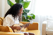 © CarlosBarquero - Online ukulele lessons from home. Young girl plays stringed instrument sitting on the sofa at home.