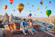 © travnikovstudio - Happy young couple during sunrise watching hot air balloons in Cappadocia, Turkey