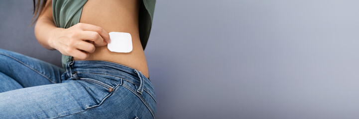woman applying patch on her body