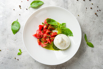 Wall Mural - Salad with buratta cheese and tomatoes on bowl on grey table top view