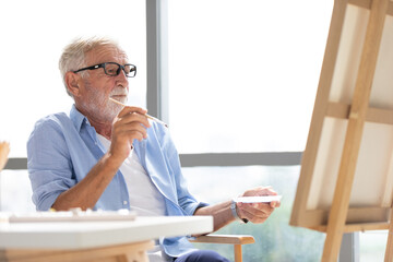 Wall Mural - senior man painting a picture from paintbrush in free time