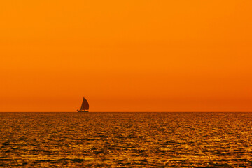 Wall Mural - Silhouette of a sailing boat in sunset sunrise time and ocean horizon.