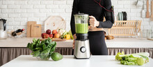 Young Blond Smiling Woman Making Green Smoothie At Home Kitchen